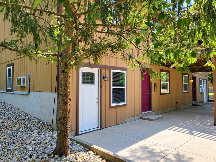Hidden Pines townhome entrances and a paved patio shaded by pine branches